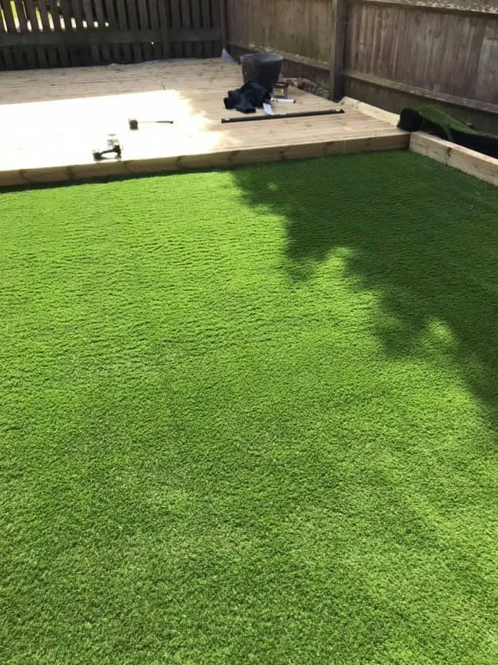 Artificial grass with a timber deck and garden boundaries